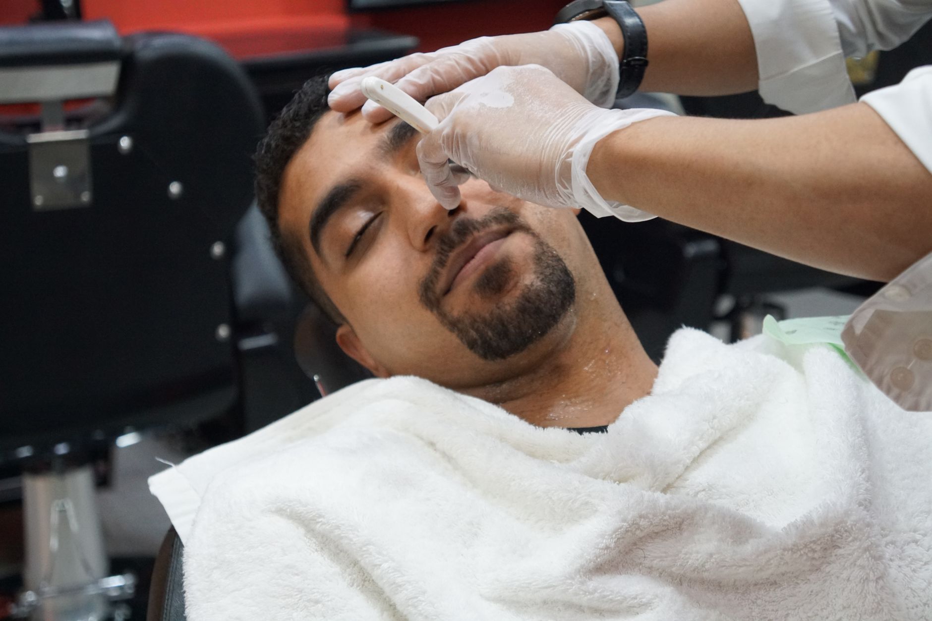 Barbero de Navaoro afeitando con navaja recta bajo luz cálida
