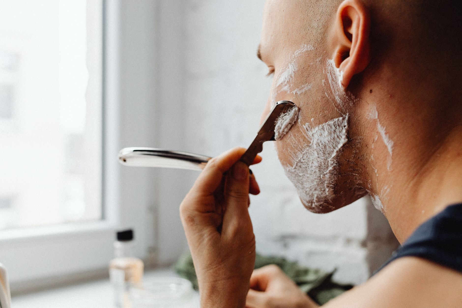 Barbero afeitando con navaja y espuma